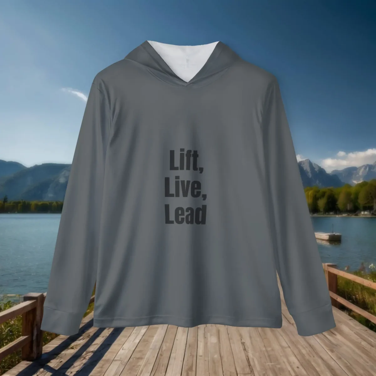 Flat lay of gray hoodie with “Lift, Live, Lead” text displayed on a scenic wooden boardwalk near a mountain lake.