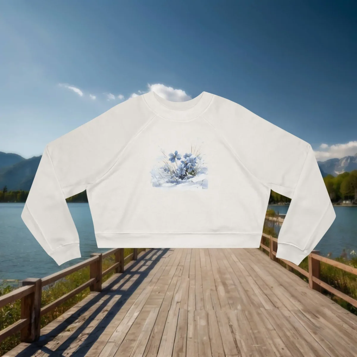 Flat lay of a white cropped sweatshirt with soft blue flowers in a watercolor style