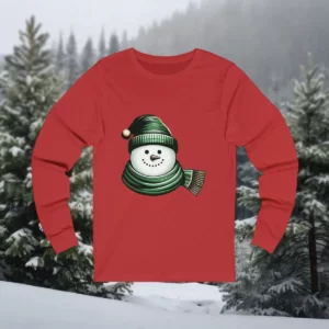 Long-sleeve shirt featuring a smiling snowman wearing a cozy green hat and matching scarf, set against a snowy forest background.