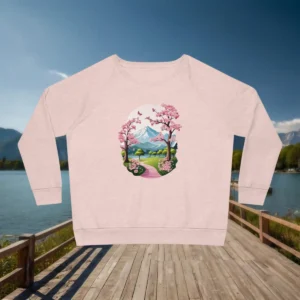Flatlay of a light pink sweatshirt with an illustrated cherry blossom park and mountain landscape