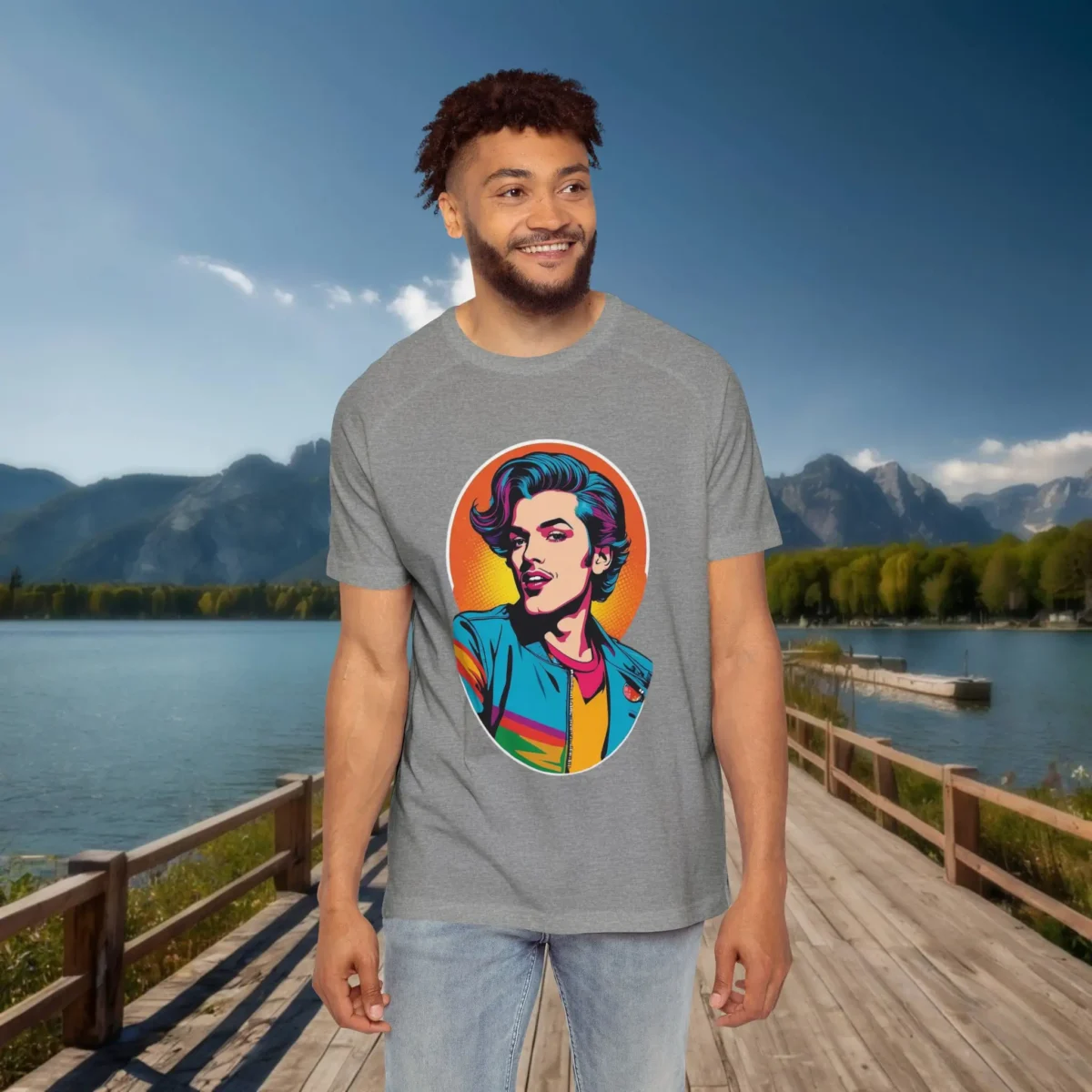 Man wearing a grey raglan t-shirt with a colorful pop art illustration of a stylish man in a retro outfit, standing on a dock with a mountain and lake background.