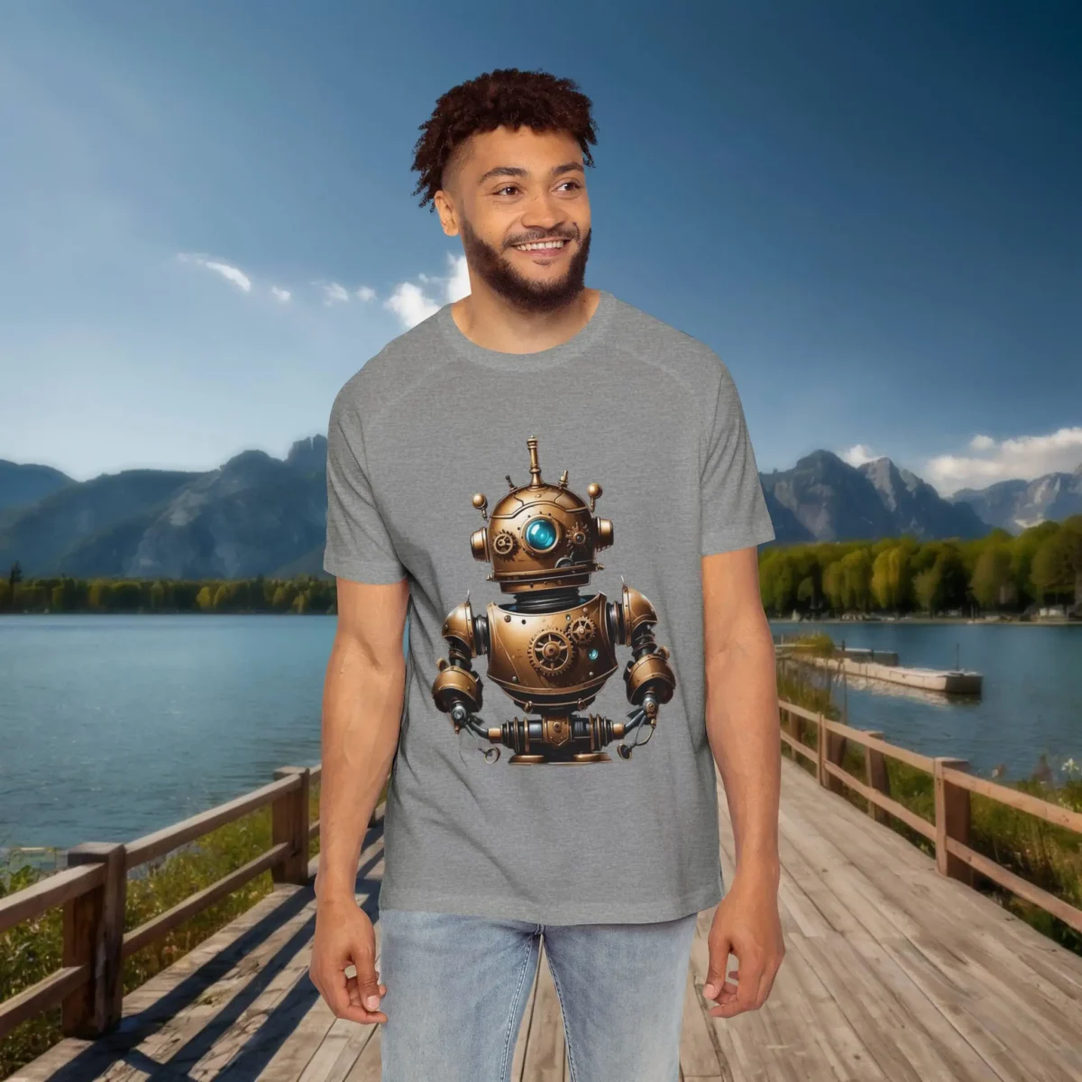 Man wearing a grey raglan t-shirt with a detailed steampunk-style bronze robot design, posed on a dock with lake and mountain scenery.