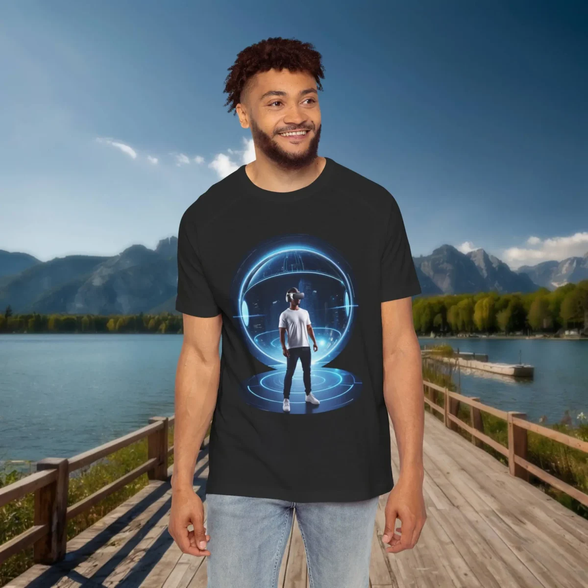 Man wearing a black raglan t-shirt with a futuristic virtual reality illustration showing a person inside a glowing blue digital sphere, standing on a dock with mountains in the background.