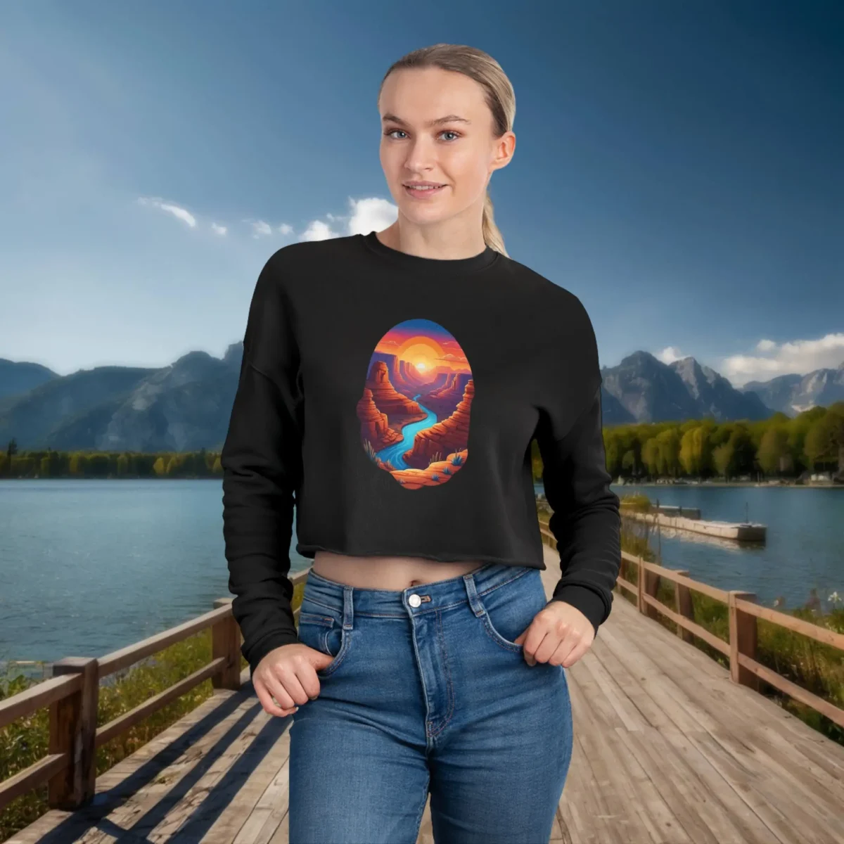 Woman wearing a black cropped sweatshirt with a colorful canyon landscape and sunset illustration