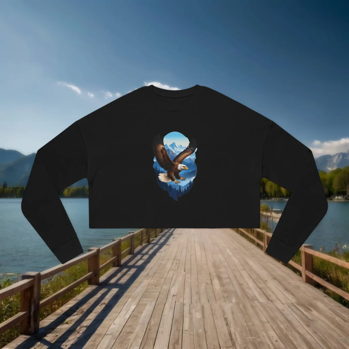 Flat lay of a black cropped sweatshirt with a soaring eagle and mountain illustration