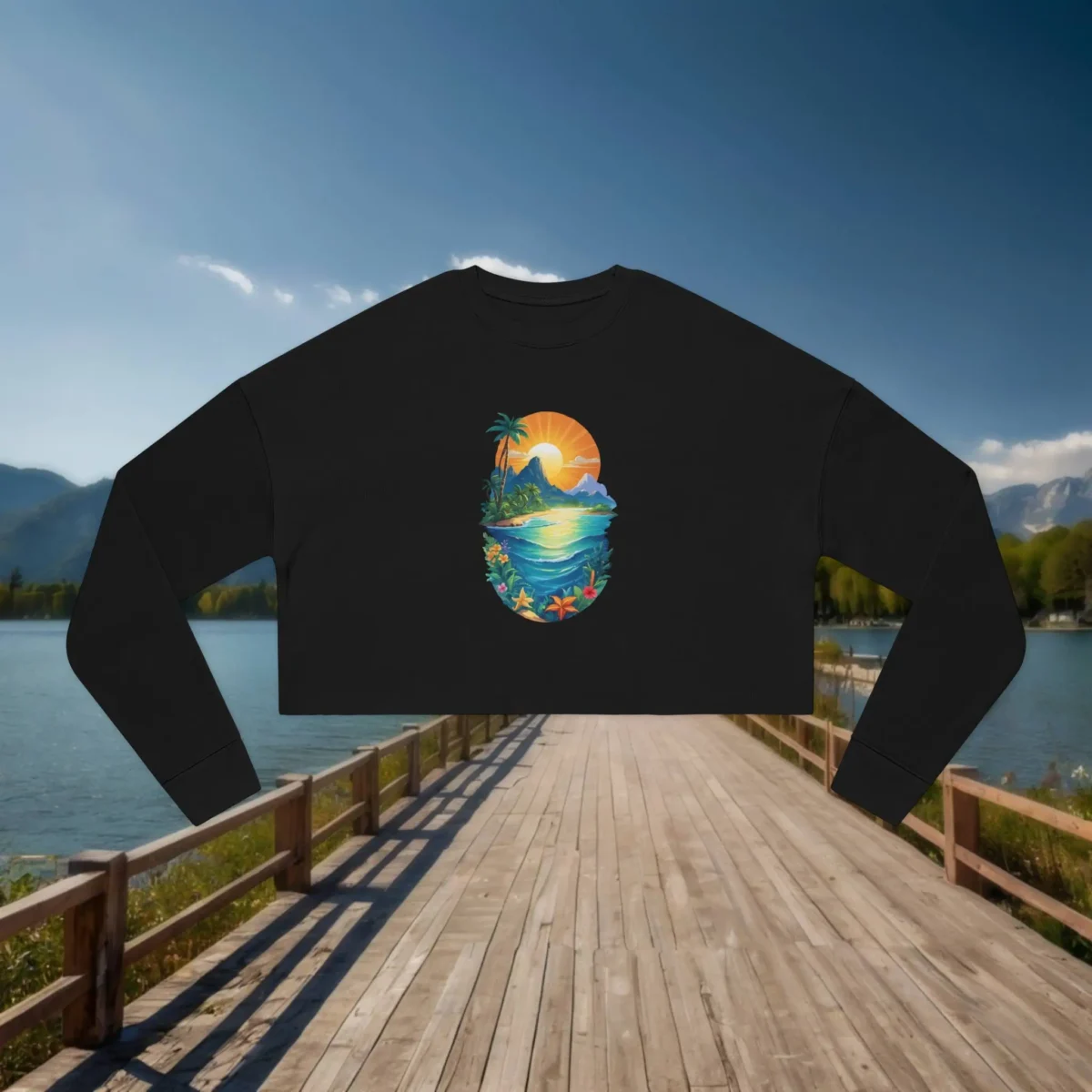 Flat lay of a black cropped sweatshirt with a vibrant tropical island sunset design