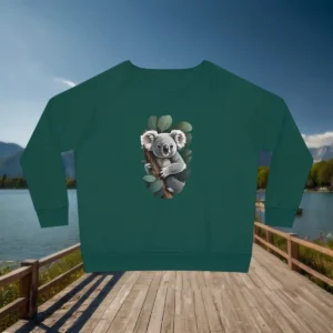 Flat lay of green sweatshirt with cute koala design, shown on a boardwalk by a lake