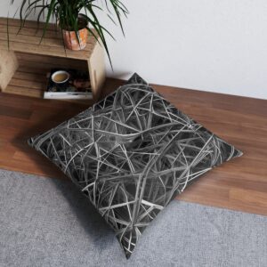 Black and white geometric tufted floor pillow with intersecting lines on a cozy room corner