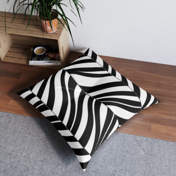 Minimalist black and white tufted floor pillow with a wave-like stripe pattern