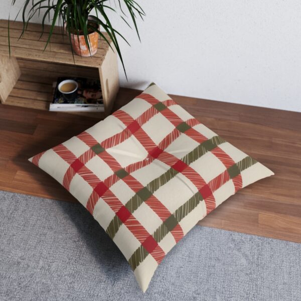 Square tufted floor pillow with red and green plaid pattern on cream background