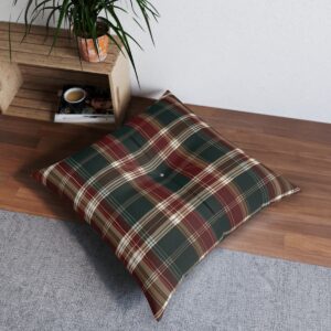 Square tufted floor pillow with a plaid pattern in deep red, forest green, and earthy brown on a wooden floor