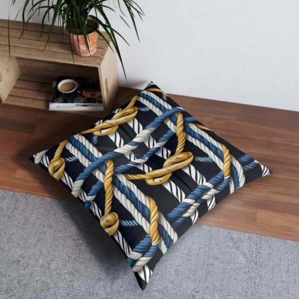 Tufted floor pillow with golden knotted ropes meeting navy stripes