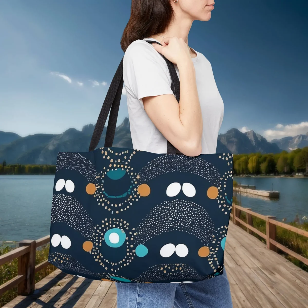 Woman wearing a navy blue weekender tote bag with abstract polka dot pattern in white, teal, and gold