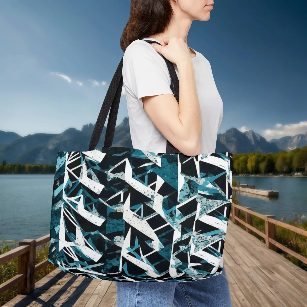 Woman wearing a weekender tote bag with abstract triangle pattern in black, teal, and white