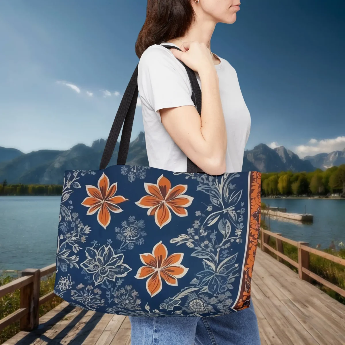 Woman holding a weekender tote bag with a blue batik floral design and orange accents