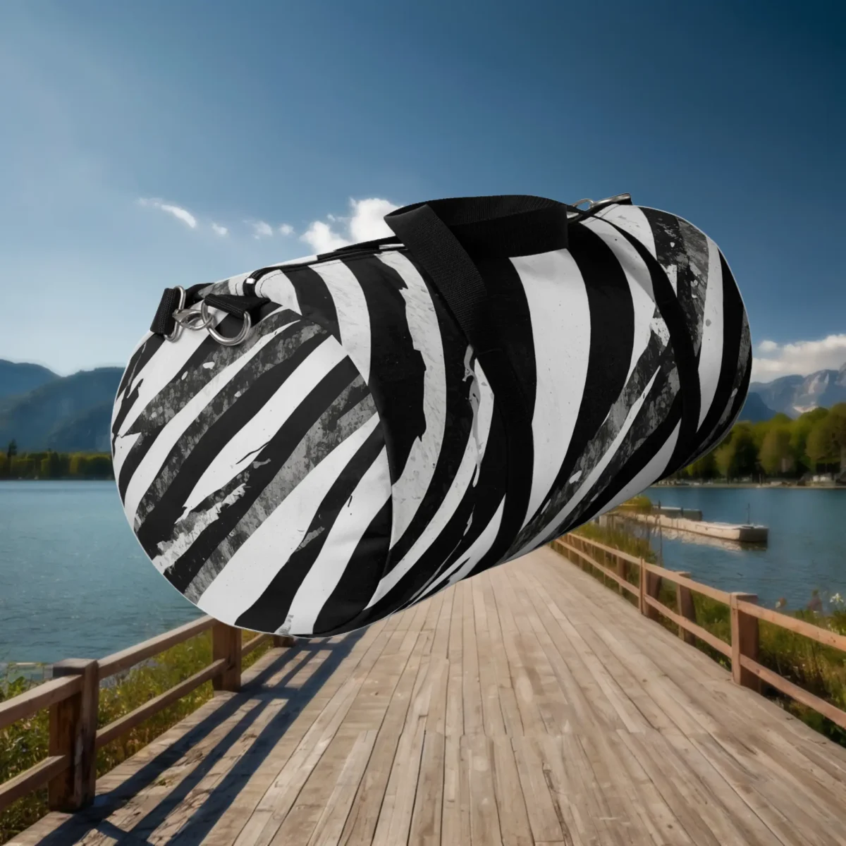 Large black and white abstract striped duffel bag shown from an angled side view over a wooden pier.