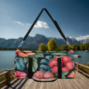 Large duffel bag with vivid hibiscus floral print on a black background, suspended by black shoulder strap.