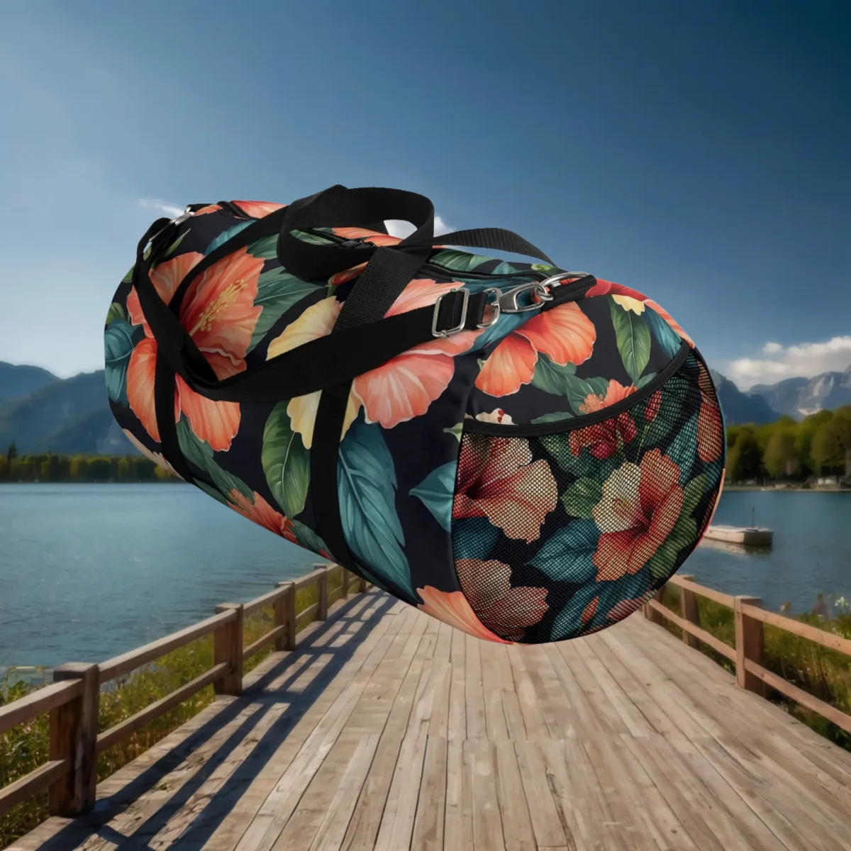 Side view of large hibiscus floral duffel bag with mesh end pocket and black strap.