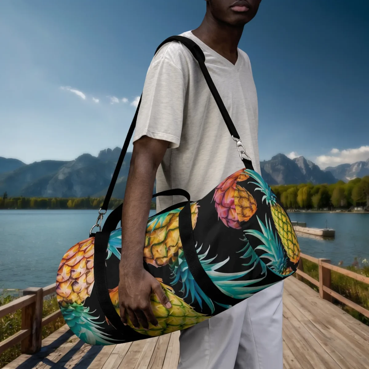 Man holding a large duffel bag with multicolored pineapple design, worn on shoulder.