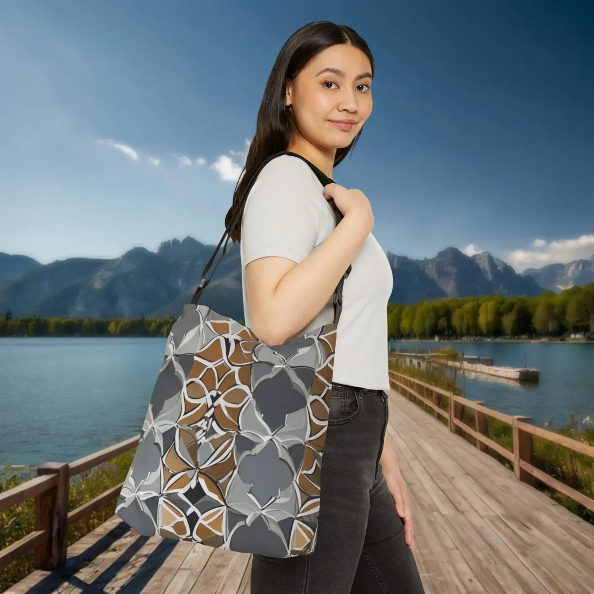 Woman carrying Moroccan pattern tote bag on shoulder by a lakeside boardwalk with mountains in the background.