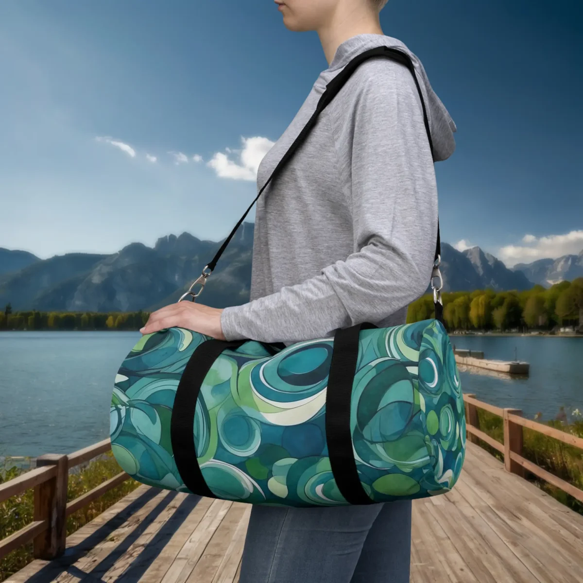 Woman carrying a small duffel bag with abstract green and blue overlapping circle design.