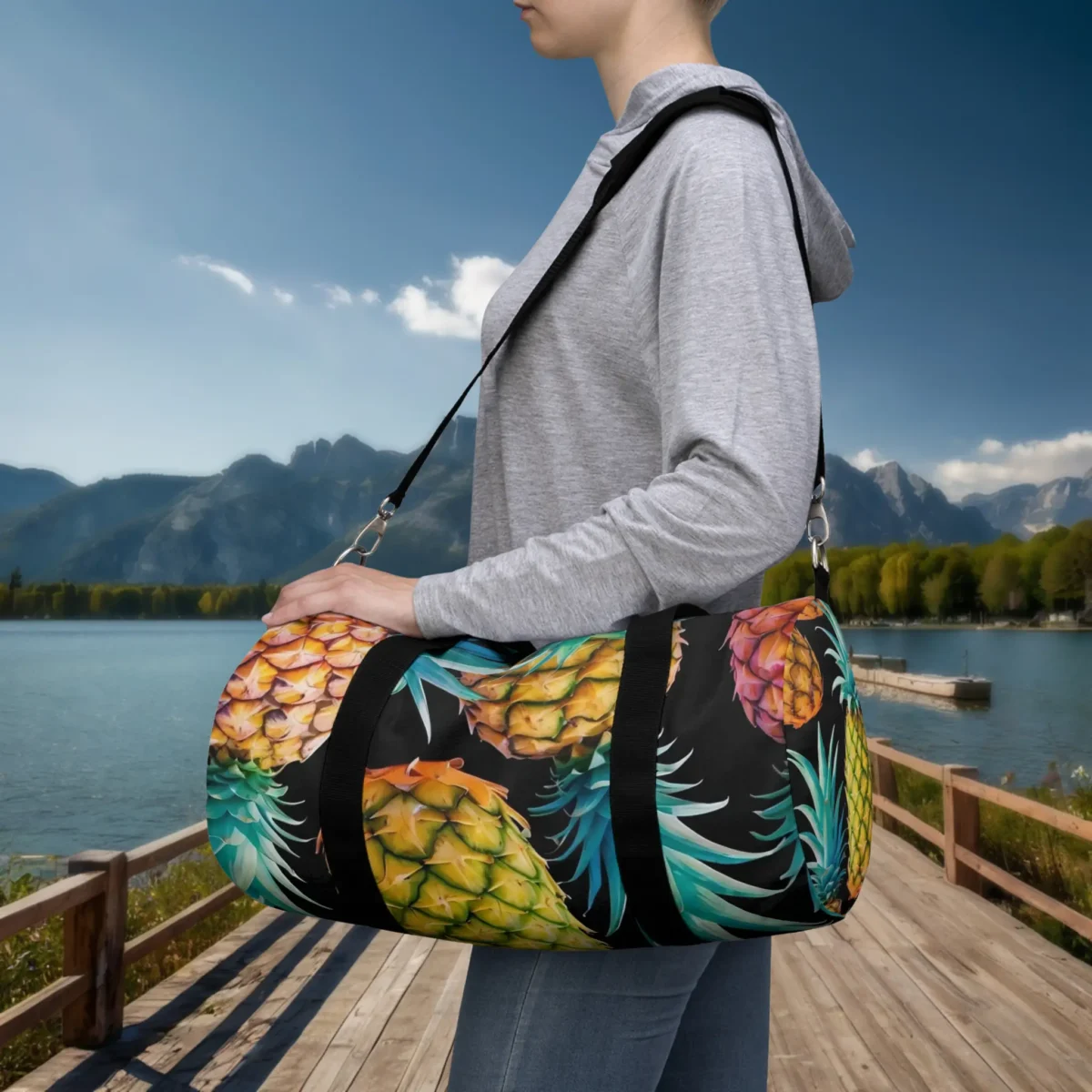 Woman wearing a small duffel bag with colorful pineapple pattern on black background.