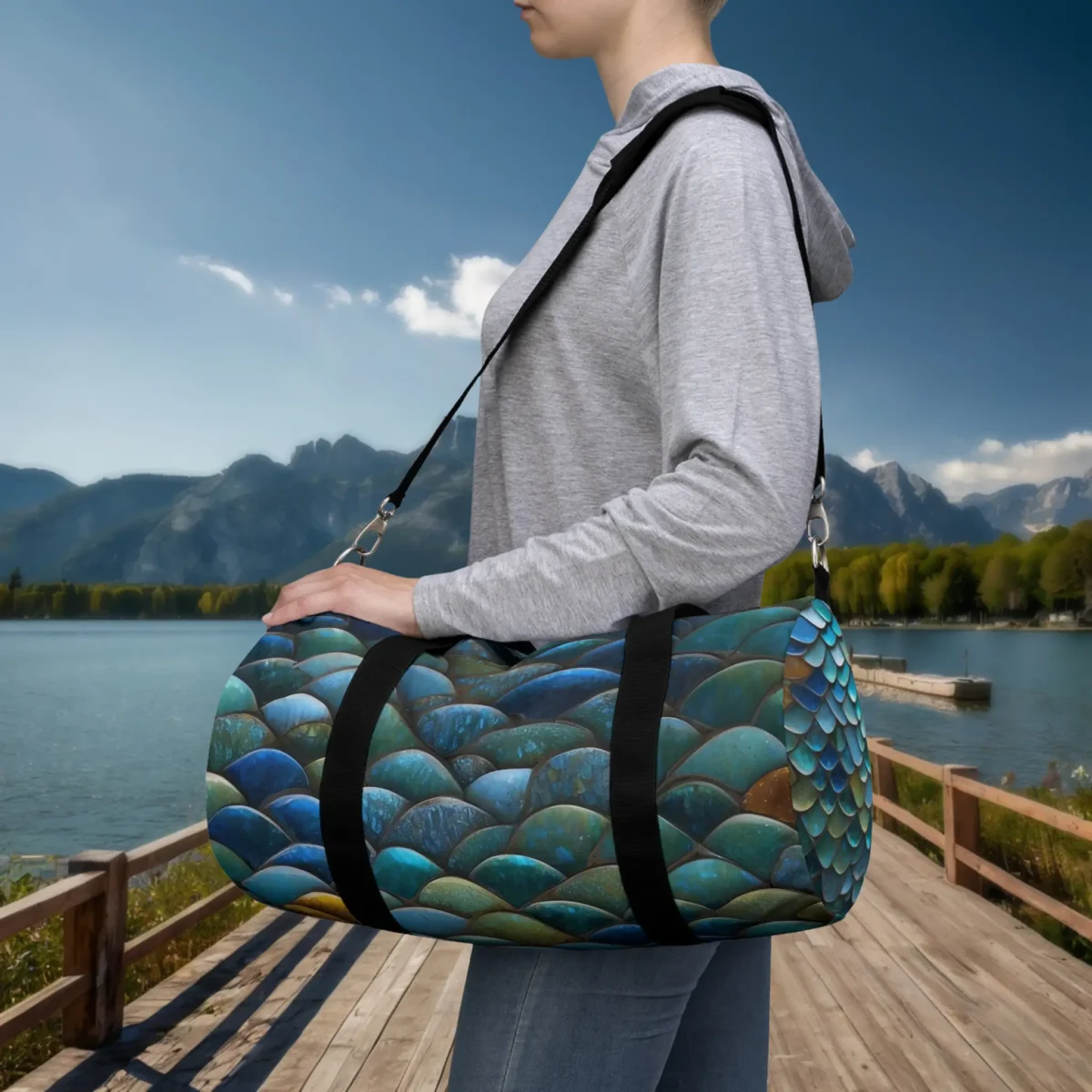 Woman carrying a small duffel bag with tropical fish scale pattern in blue and green tones.