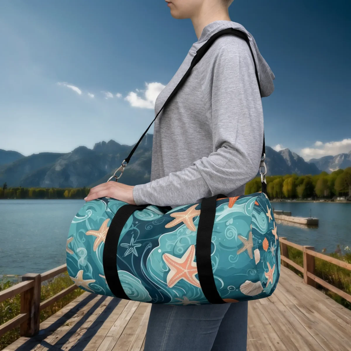 Woman carrying a small duffel bag with ocean wave pattern and starfish illustrations.