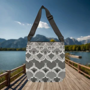 Flat view of Starburst Tile tote bag featuring a grayscale geometric tile pattern, placed on a wooden boardwalk near a lake and mountains.
