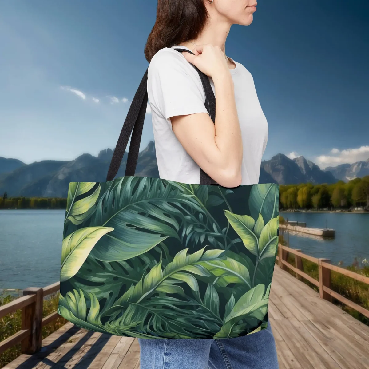 Woman carrying a weekender tote bag with tropical leaves print in green shades