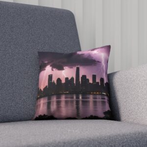 Decorative cushion with cityscape and reflective stormy sunrise over water on sofa