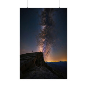 Person standing on cliff edge beneath the Milky Way in the night sky