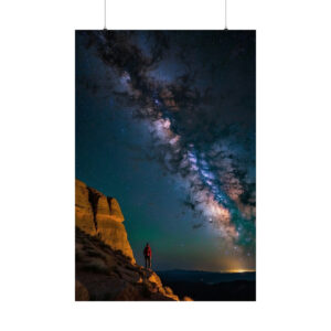 Person standing on rocky landscape under a vivid Milky Way night sky