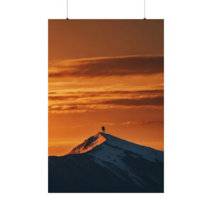 silhouette of a person standing on a snowy mountain peak at sunset