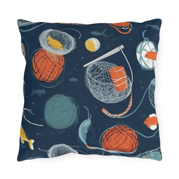 Outdoor pillow with dark blue background featuring fishing nets, buoys, and fish design