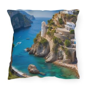 outdoor pillow featuring a cliffside lighthouse, turquoise waters, and coastal village with rocky cliffs