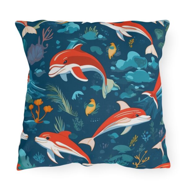 outdoor pillow featuring red dolphins and tropical fish swimming in a deep blue ocean background