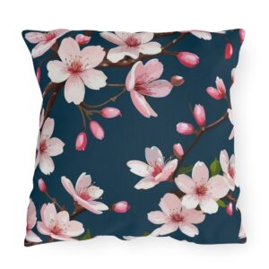 Outdoor pillow with pink cherry blossoms on a dark teal background.