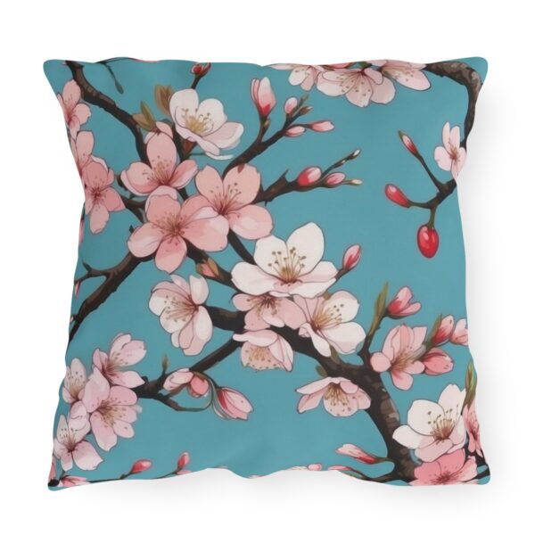 Outdoor pillow with pink cherry blossoms on a turquoise background.