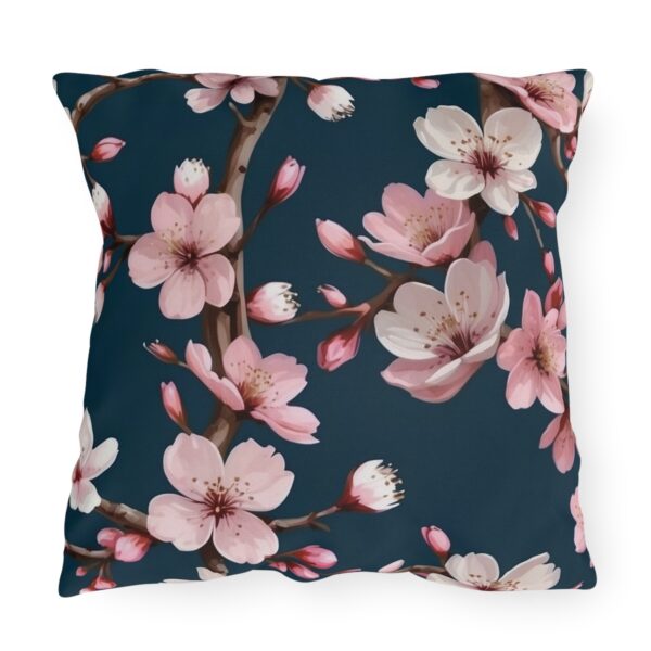 Outdoor pillow with pink cherry blossoms on a dark blue background.