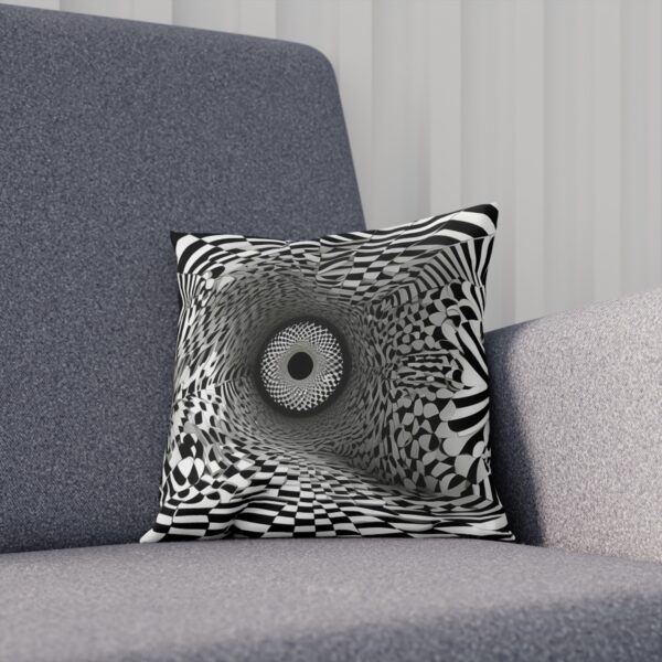 Black and white hypnotic pattern cushion placed on a modern grey sofa.