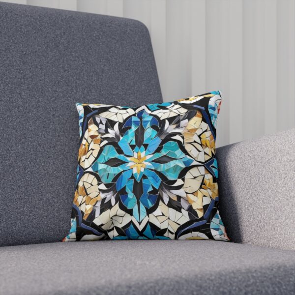 Cushion with blue and beige mosaic tile pattern on a gray couch.