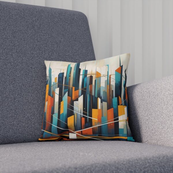 Abstract cityscape cushion with teal, orange, and cream colors on a grey sofa.