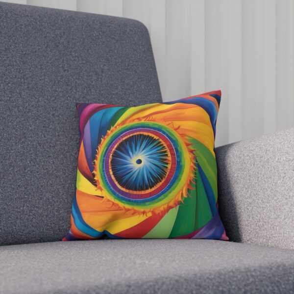 Rainbow-colored cushion with central eye pattern on a grey sofa.