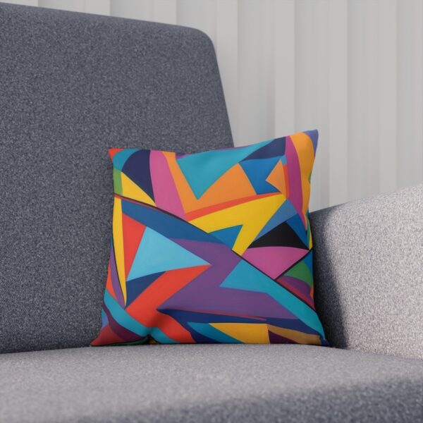 Cushion with colorful angular geometric design on a gray sofa.