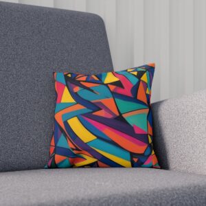 Cushion with vibrant abstract geometric shapes on a grey sofa.