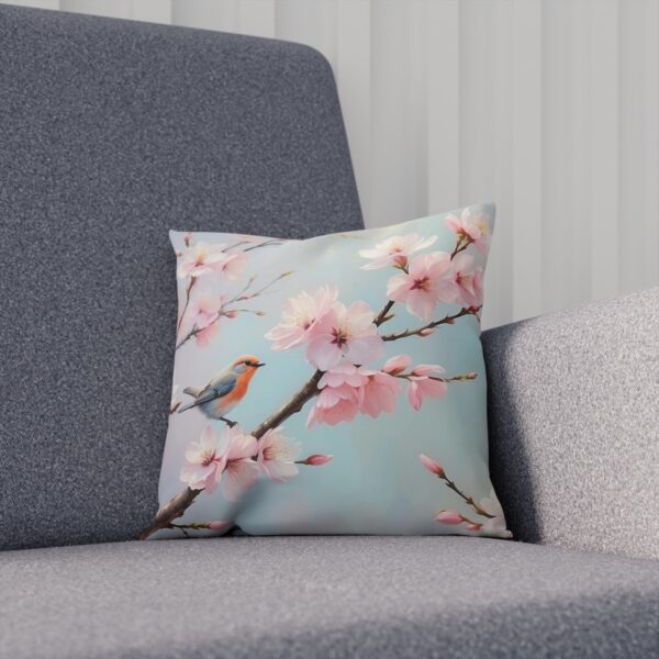 Cushion with cherry blossoms and bird on blue background on sofa