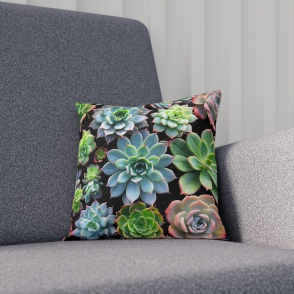 Cushion with a mix of green succulents on dark backdrop on sofa