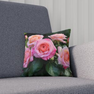 Cushion featuring pink roses against lush green leaves