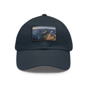 Navy dad hat with a leather patch showing a mountainous sunset landscape.